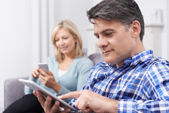 Man viewing his tablet while woman views smartphone