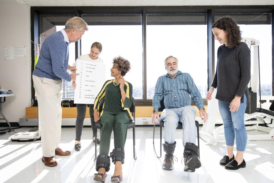 A woman and man sit in chairs while clinicians speak with them