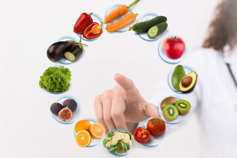 Fruits and vegetables are pictured in a circle on a white background next to a person wearing a white lab coat.